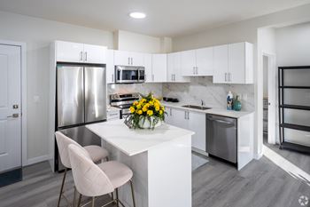 A modern kitchen with a white island and a refrigerator.